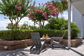 Patio esterno con due poltrone Adirondack, un tavolo e una bevanda.