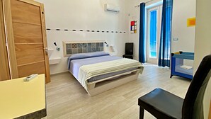 Ein Schlafzimmer mit Bett, Schreibtisch, Stuhl, einem Fenster mit Vorhängen und einem Dachfenster an der Decke.