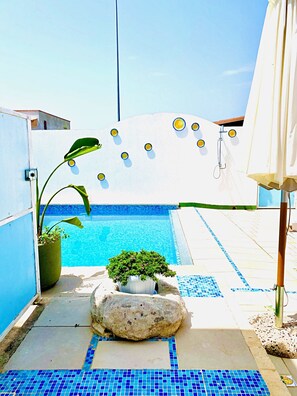 A pool area with a tiled floor, a large rock, and a potted plant. - Casa Mondrian - Camere con Bagno e Piscina Privata (Tiggiano)