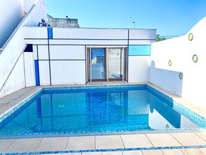 A modern pool area with a clear blue pool, tiled deck, and a white building with blue accents. - Casa Mondrian - Camere con Bagno e Piscina Privata (Tiggiano)