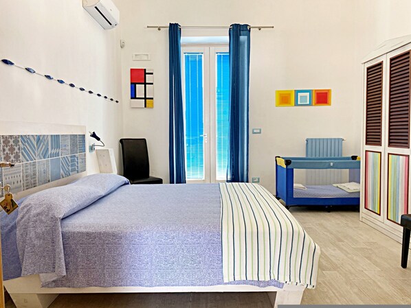 A bedroom with a bed, a chair, a small bunk bed, and a window with curtains.