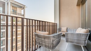 Un balcón con mobiliario de mimbre y vistas de edificios cercanos.