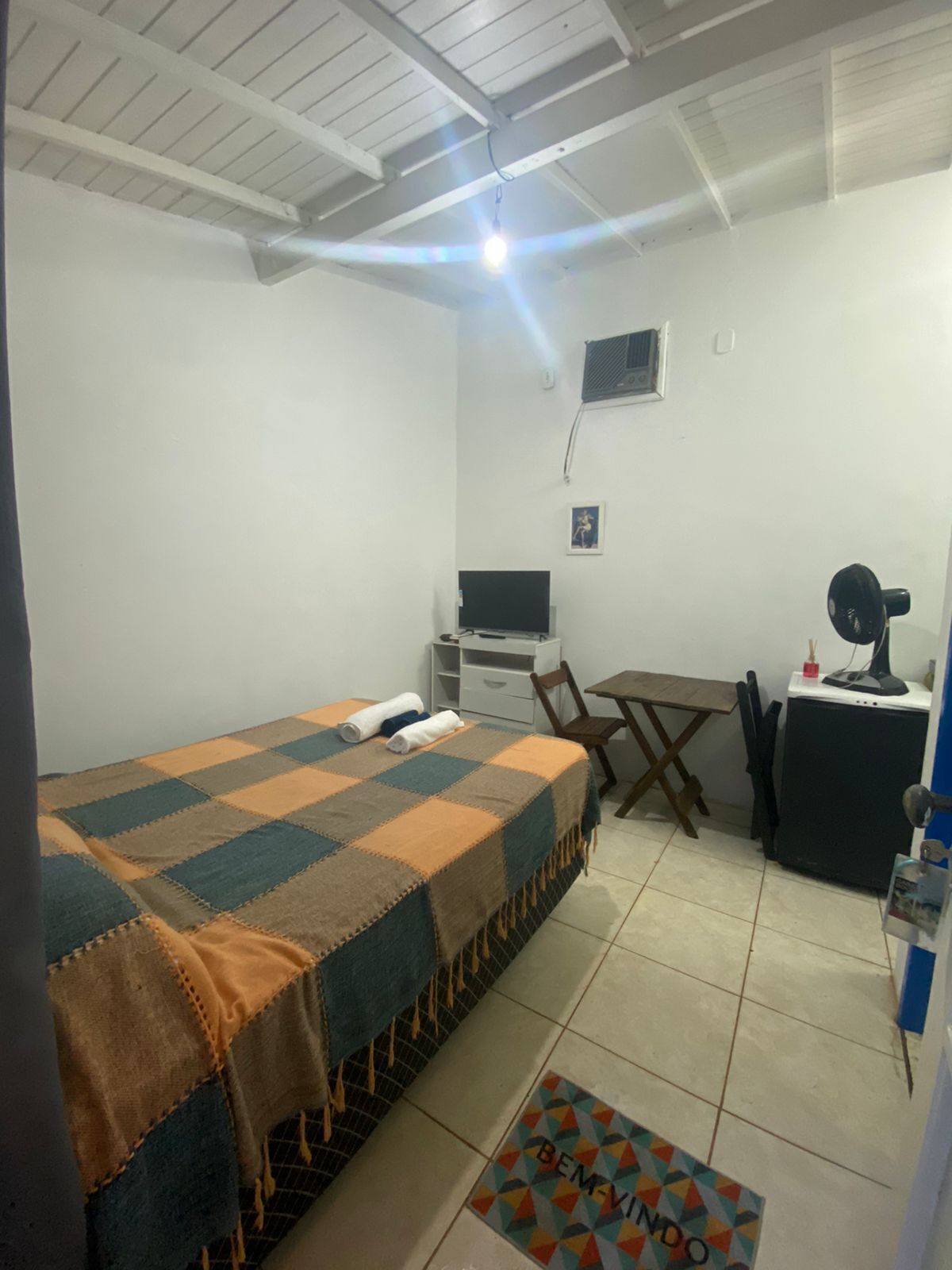 A small, clean room with a bed, a desk, a chair, and a computer.