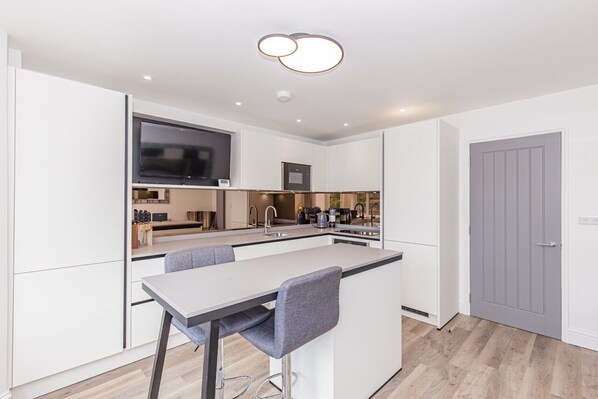 A modern kitchen with a bar area, built-in appliances, and a grey door. - Luxury 2 Bedroom, 2 Bathroom Apartment - Oxford (Oxford)