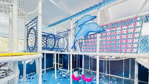 Een overdeelde speelruimte met meerdere niveaus van netten constructies, een blauwe vloer en verschillende ballen verspreid.