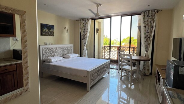 A bedroom with a bed, a desk, and a TV. - Mulla Apartments  (Malindi)