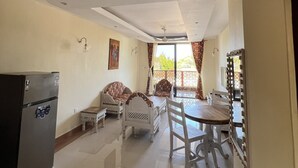 A spacious living area with a dining table and chairs, a sofa, a refrigerator, and a ceiling fan. - Mulla Apartments  (Malindi)