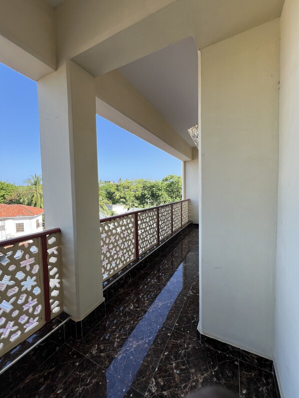 A corridor with a marble floor, white walls, and a decorative metal railing.