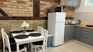 A kitchen with a brick wall, a white refrigerator, a microwave, a sink, and a window. - Apartments Badallee 4, Bad Schandau, apartment no. 8, 50m2 (Bad Schandau)