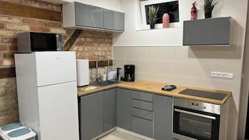 Een kleine keuken met een koelkast, magnetron, spoelbak en oven.