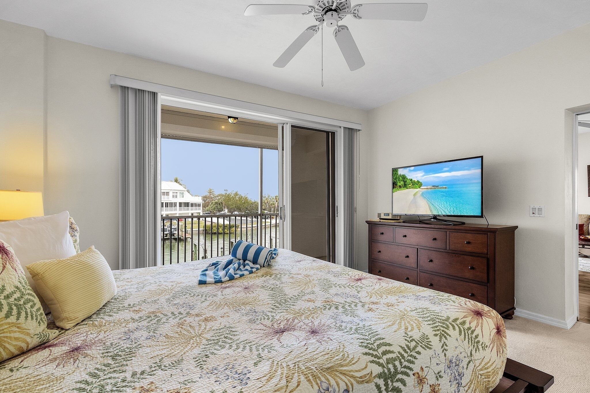 Una camera da letto con un letto, una televisione, un comò e un balcone vista mare.