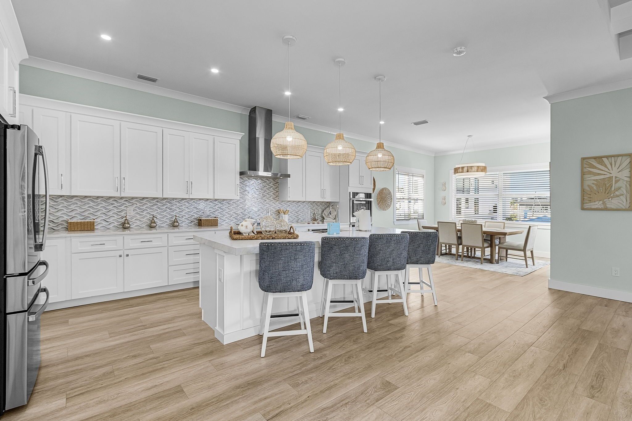 A modern kitchen with white cabinets, a central island with bar stools, and pendant lighting.