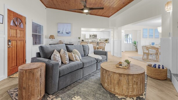 Un salon spacieux avec un canapé gris, un plafond en bois et une table basse ronde.