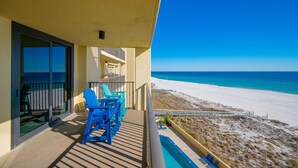 A balcony with a view of a beach, a pool, and blue chairs. - Phoenix Iv 4052 1 Bedroom Condo (Orange Beach)