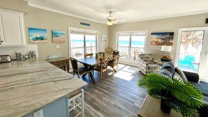 A spacious kitchen with a marble countertop, wooden dining table, and chairs. There are two large windows with views of the beach. - Beachfront Duplex in Morgantown (Gulf Shores)