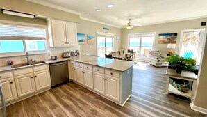 A spacious kitchen with white cabinets, a large island, and a view to the outside. - Beachfront Duplex in Morgantown (Gulf Shores)