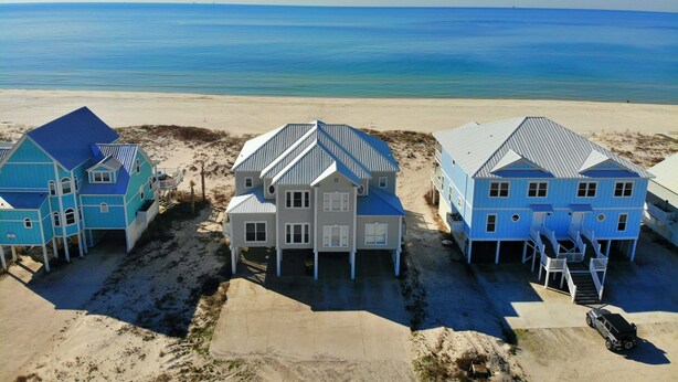 A beachfront property with three houses, a sandy beach, and the ocean in the background. - Beachfront Duplex in Morgantown (Gulf Shores)