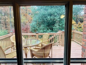 A wooden deck with wicker furniture and a glass table, overlooking a forested area. - Sleep 10 Newly Listed Vacation Home in Acworth near many restaurants & groceries (Acworth)