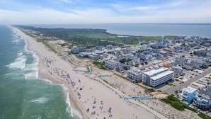 Vue aérienne d’une ville côtière avec une plage, des bâtiments et un château d’eau.