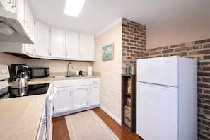 A compact kitchen with white cabinets, a microwave, a kettle, and a refrigerator. - Capitol Hill Charm + Walk to Union Station + Free Parking (Washington)