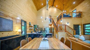 A spacious wooden cabin with a dining area, kitchen, and a loft bedroom. - Stylish Cabin Near Broken Bow Lake & Casino + Firewood Provided (Broken Bow)