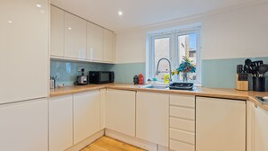 Una cocina moderna con armarios blancos, encimera de madera, un lavabo y una ventana con vistas al exterior.