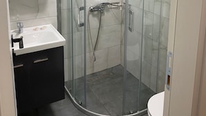A modern bathroom with a glass-enclosed shower, a white sink, and a mirror above the sink. - Comfort Room -A- (Marmaris)