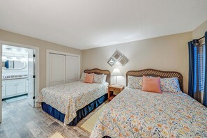 Une chambre avec deux lits, une armoire, un miroir et une table de chevet avec une lampe.