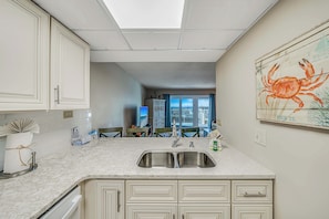 A kitchen with a double sink, white cabinets, and a large window.