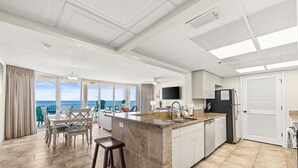 Una cocina amplia con una isla grande, un comedor con vistas y un diseño de techo moderno.