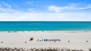 Una playa con una fila de sillas, una torre de salvavidas y arena al frente.