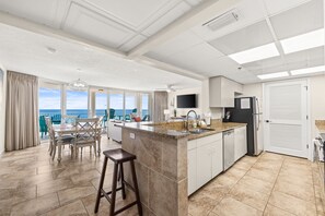Una cocina amplia con una isla grande, un comedor con vistas y un diseño de techo moderno.