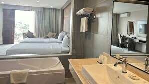 A modern hotel room with a large bed, a sitting area with a view, a bathroom with a bathtub and sink, and a large mirror. - Muong Thanh Grand Gia Lai (Pleiku)
