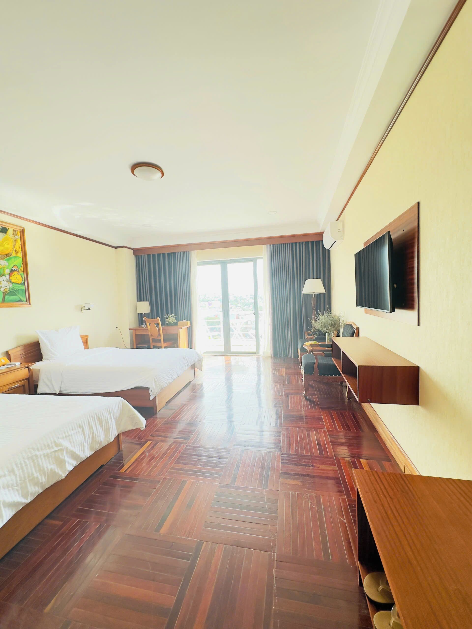 Habitación de hotel con dos camas, televisión, escritorio y vistas al exterior.