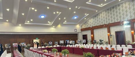 A conference room with long tables, white chairs, and floral centerpieces.