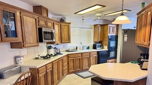 Una cocina con armarios de madera, microondas, horno, lavavajillas y fregadero.