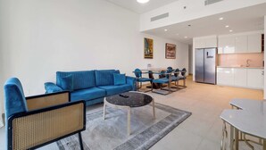 Un salon moderne avec un canapé bleu, une table basse et un coin repas comprenant des chaises et une table.