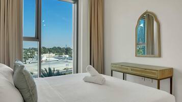 Una habitación de hotel con un ventanal grande, una cama, una mesita de noche y un espejo.