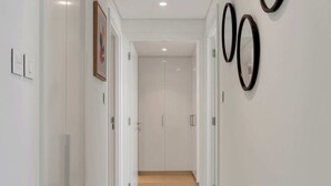 Un couloir aux murs blancs, doté d’un sol carrelé et orné de trois décorations murales circulaires noires.