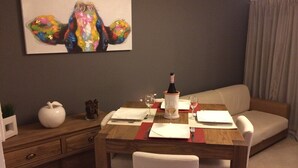 A dining area with a wooden table set for two, a bottle of wine, and a painting on the wall. - Apartment 500 m from seafront and center of Ile Rousse (L'Île-Rousse)