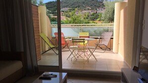 A balcony with a table and chairs, a sofa, and a TV. - Apartment 500 m from seafront and center of Ile Rousse (L'Île-Rousse)