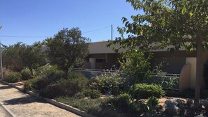 A residential area with a paved road, a small garden with various plants and flowers, and a building with a flat roof in the background. - Apartment 500 m from seafront and center of Ile Rousse (L'Île-Rousse)