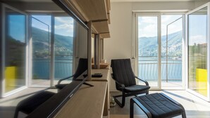 Ein modernes Zimmer mit großem Fenster, Schreibtisch, Stuhl und kleinem Tisch.