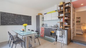 Eine moderne Küche mit einer Kreidetafel, einem Esstisch mit Stühlen und einer kleinen Kücheninsel mit Spüle.
