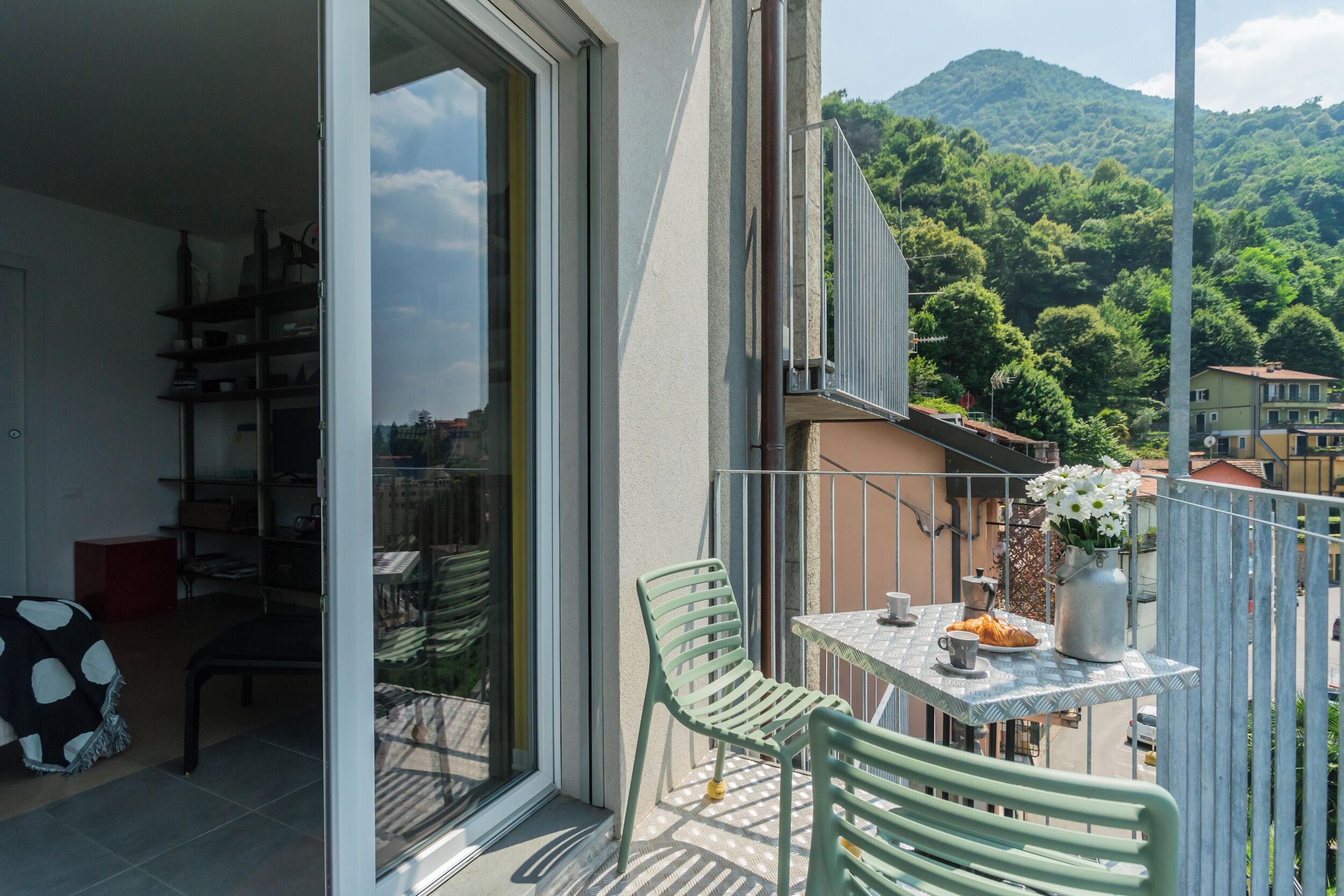Un balcon avec une table, des chaises et un vase de fleurs.