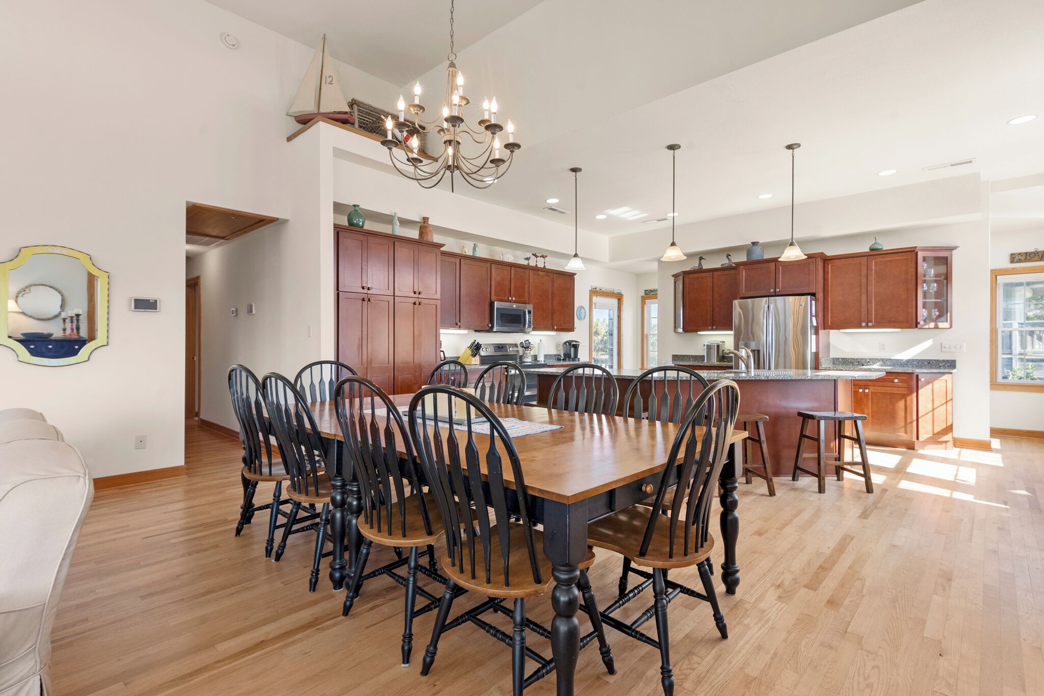 A spacious kitchen with wooden cabinets, a central island, and a chandelier.