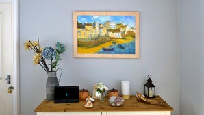 Een houten dressoir met een schilderij, een vaas met bloemen, een kaars en een lantaarn.