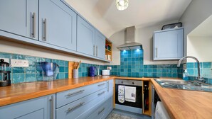 A kitchen with blue cabinets, a wooden countertop, a built-in oven, and a sink.