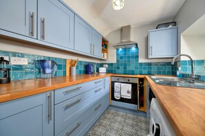 A kitchen with blue cabinets, a wooden countertop, a built-in oven, and a sink.