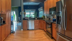 A modern kitchen with wooden cabinets, stainless steel appliances, and a central island. - Everyday Your Beachside Escape! (Cape Charles)